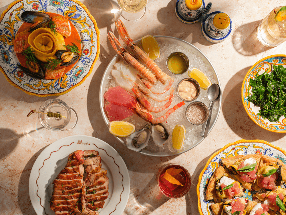 Delicious spread of Italian dishes on a table with cocktails at Alassio restaurant in Florence.